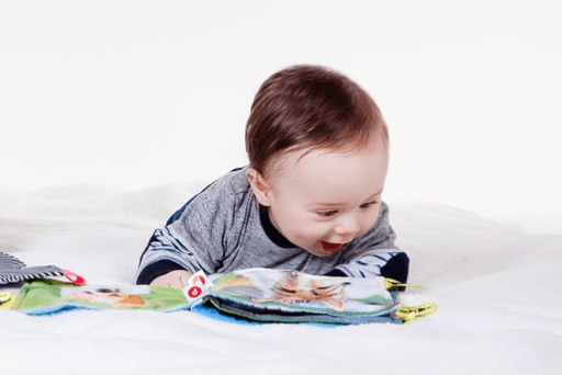 A happy baby looking at a book